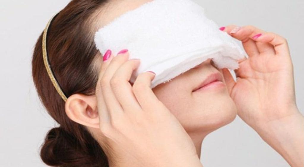 Sử dụng khăn ướt đắp lên mắt để làm mềm lớp keo và giảm tình trạng đau rát ở mắt